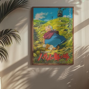 May include: Framed poster featuring an animated character in a blue dress and red shawl, walking on a green hillside. The poster has Japanese text and is set in a wooden frame. A potted plant is in the foreground.
