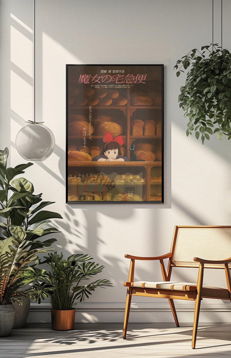 May include: A framed poster featuring a scene from the animated film, Kiki's Delivery Service. The poster shows a young girl with a red bow in her hair, looking out from behind a bakery counter filled with bread. The Japanese title is visible.