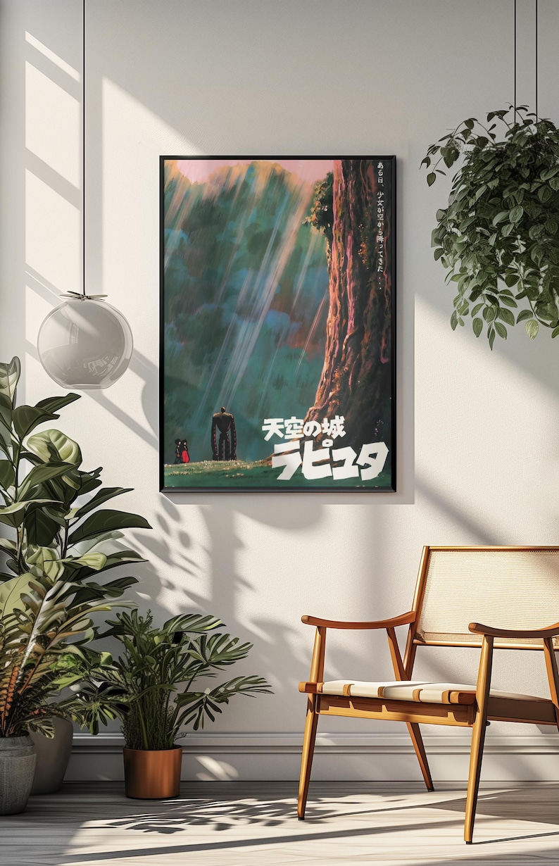 May include: A framed poster with Japanese text and imagery from the animated film "Castle in the Sky." The artwork shows a large figure and two smaller characters in a forest, with light beams shining through the trees. The poster is in a black frame.