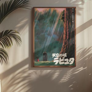 May include: A framed poster with Japanese text and artwork from the animated film "Castle in the Sky." The artwork shows a forest scene with a large tree, a figure, and a small creature. The poster is in a wooden frame.