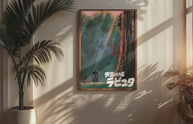 May include: A framed poster with Japanese text and artwork from the animated film "Castle in the Sky." The artwork shows a forest scene with a large tree, a figure, and a small creature. The poster is in a wooden frame.