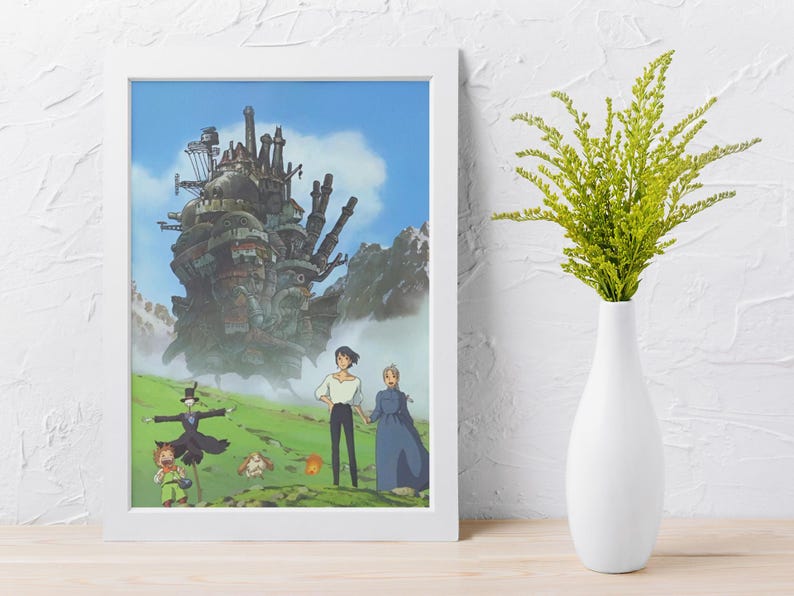May include: Framed print of an animated movie scene featuring a large, complex structure with smokestacks against a blue sky. Characters stand in a green field. A white vase holds green plants.