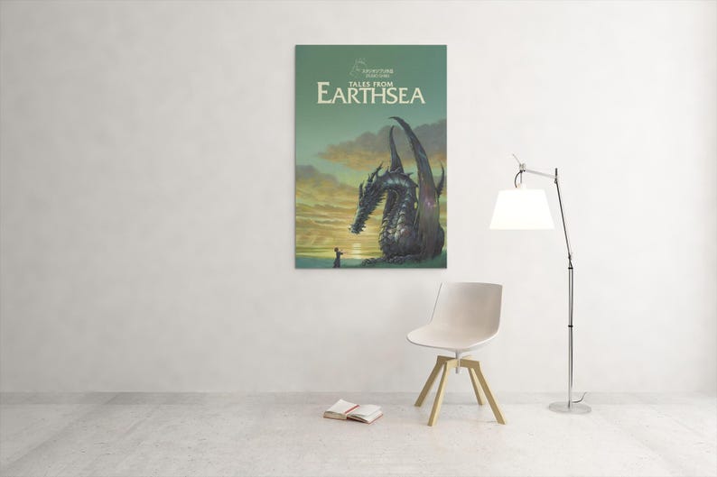 May include: A framed poster of "Tales from Earthsea" featuring a dragon and a person. The poster is mounted on a white wall. A white chair, a book, and a lamp are in the foreground.