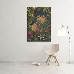 May include: A framed poster of "The Secret World of Arrietty" anime film. The artwork features a young boy peering through foliage at a tiny person in a bottle. The title is displayed in elegant script. The poster is mounted on a white wall.