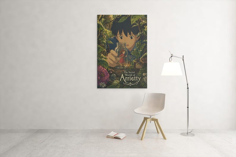May include: A framed poster of "The Secret World of Arrietty" anime film. The artwork features a young boy peering through foliage at a tiny person in a bottle. The title is displayed in elegant script. The poster is mounted on a white wall.