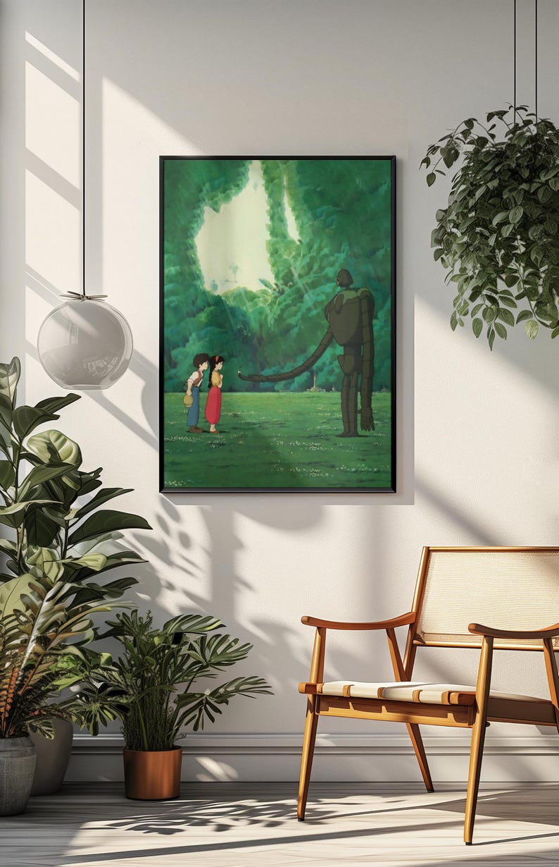 May include: A framed wall art print featuring a scene from an animated film. The image depicts two small figures standing in a lush green field, facing a tall, slender, dark-colored robot that extends one long arm toward them in a forest setting.