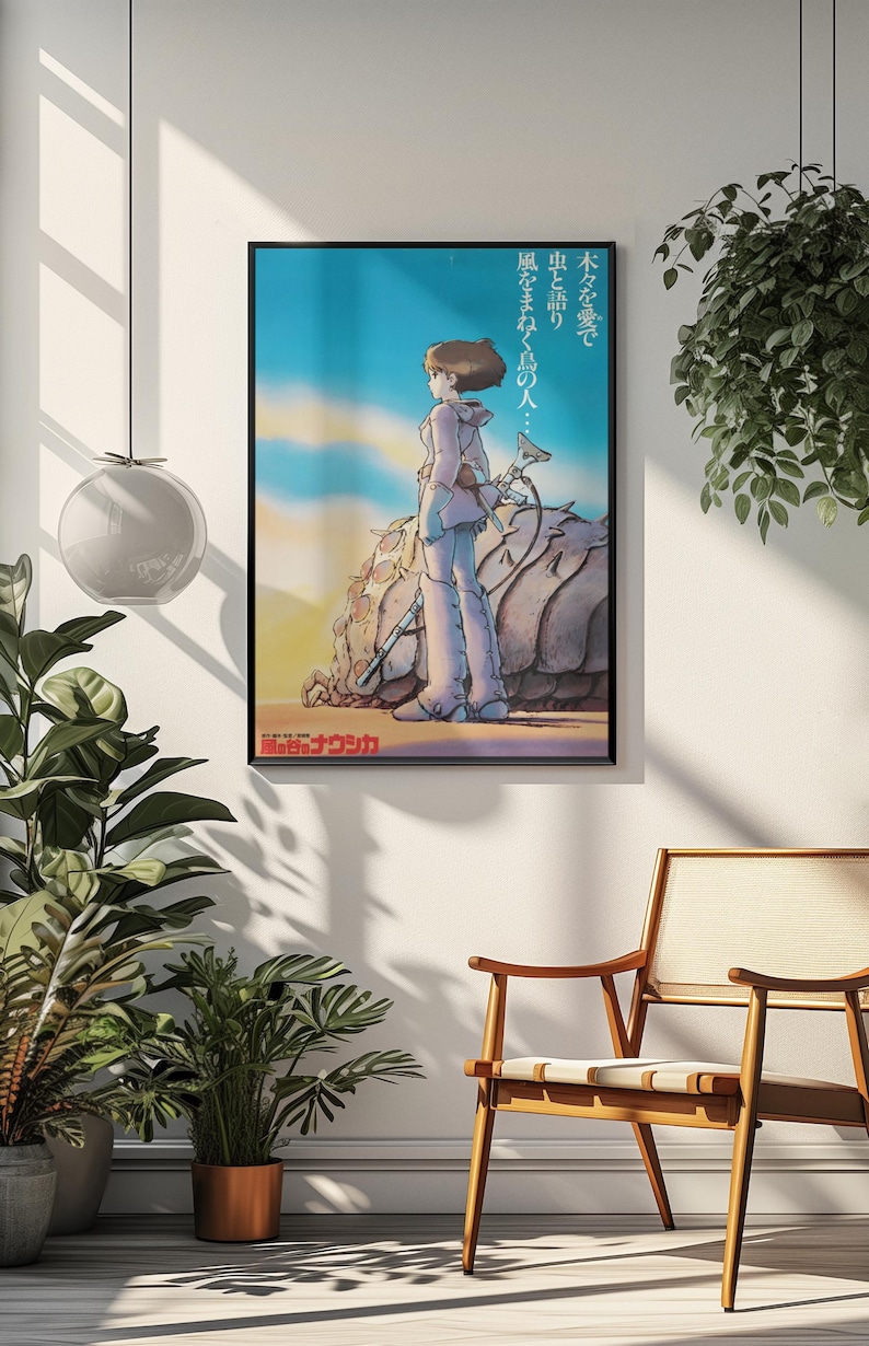 Puede incluir: P&oacute;ster de anime enmarcado con un personaje con ropa clara de pie sobre un paisaje rocoso, con texto japon&eacute;s. El fondo muestra un cielo azul con nubes. El p&oacute;ster se exhibe en una pared blanca con plantas y una silla de madera.
