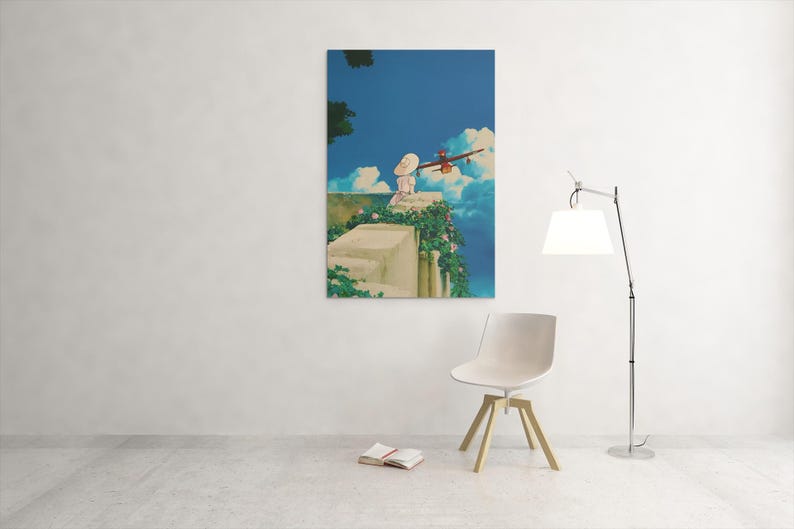 May include: A framed art print depicts a scene with a person in a white dress and hat, overlooking a blue sky with clouds and a red airplane. The artwork is mounted on a white wall, with a chair and lamp in the foreground.