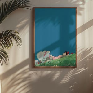 K&ouml;nnte beinhalten: Ein gerahmter Kunstdruck mit einer friedlichen Szene einer Person, die sich auf einem gr&uuml;nen H&uuml;gel unter blauem Himmel ausruht. Das Kunstwerk hat einen Holzrahmen und ist von Pflanzen in einem gut beleuchteten Raum umgeben.