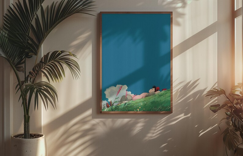 K&ouml;nnte beinhalten: Ein gerahmter Kunstdruck mit einer friedlichen Szene einer Person, die sich auf einem gr&uuml;nen H&uuml;gel unter blauem Himmel ausruht. Das Kunstwerk hat einen Holzrahmen und ist von Pflanzen in einem gut beleuchteten Raum umgeben.