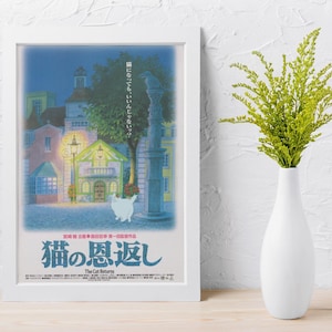 Puede incluir: Un p&oacute;ster enmarcado con una escena de la pel&iacute;cula de anime "The Cat Returns". La obra de arte representa una plaza de pueblo europea por la noche, con un gato blanco en primer plano. El p&oacute;ster est&aacute; en un marco blanco, y un jarr&oacute;n blanco con follaje verde est&aacute; a la derecha.