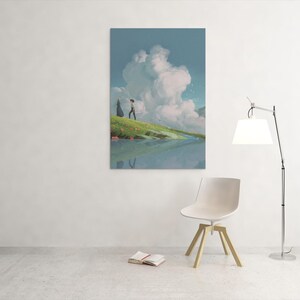 May include: A vertical art print depicts a serene landscape with a person walking on a grassy hill near a body of water. A large cloud formation dominates the sky. A modern chair, lamp, and open book are in the foreground.