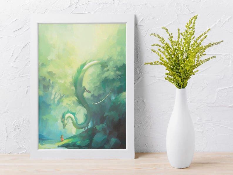May include: A framed art print featuring a fantasy scene with a green dragon, a small figure, and a lush, green forest. The artwork is in a white frame, and a white vase with green foliage is next to it.
