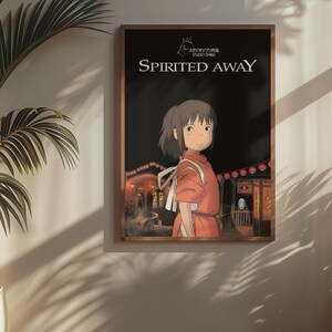 Puede incluir: Un p&oacute;ster enmarcado de la pel&iacute;cula de animaci&oacute;n "El viaje de Chihiro". La obra de arte representa a una joven con un atuendo rojo, frente a una escena nocturna con linternas y edificios. El t&iacute;tulo se muestra en texto blanco.