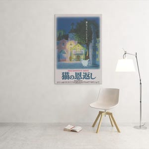 Puede incluir: Un p&oacute;ster enmarcado con texto japon&eacute;s, que representa una escena callejera nocturna con edificios y un gato blanco. El p&oacute;ster est&aacute; en una pared blanca. Una silla moderna, un libro y una l&aacute;mpara est&aacute;n en la habitaci&oacute;n.