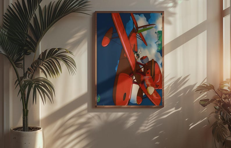 May include: A framed art print featuring a vibrant illustration of a red seaplane soaring through a blue sky with clouds. The artwork is displayed on a wall, with a potted plant in the foreground, and a window casting shadows.