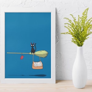 May include: A framed print featuring a black cat riding a broom against a blue background. The broom has a "Not in Service" sign and a red tag. A white vase with green foliage is on the right.