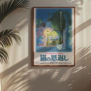 Puede incluir: Un p&oacute;ster enmarcado con una ilustraci&oacute;n nocturna de edificios, un gato y texto japon&eacute;s. El p&oacute;ster tiene un marco marr&oacute;n y cuelga de una pared beige. Una planta en maceta est&aacute; en primer plano.