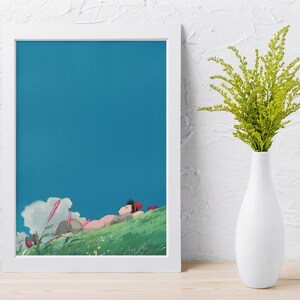 K&ouml;nnte beinhalten: Ein gerahmter Kunstdruck mit einer Szene, die eine Person zeigt, die auf einem gr&uuml;nen H&uuml;gel unter einem strahlend blauen Himmel liegt. Das Kunstwerk hat einen Cartoon-Stil mit sanften Farben. Eine wei&szlig;e Vase enth&auml;lt gr&uuml;ne Pflanzen.