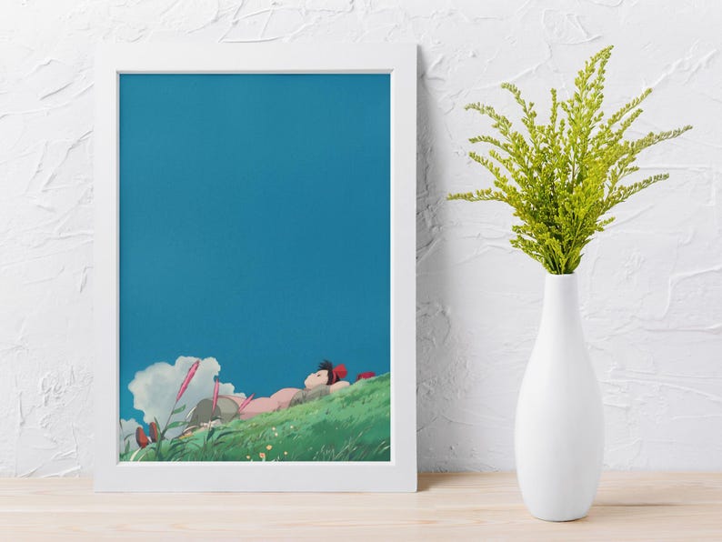 K&ouml;nnte beinhalten: Ein gerahmter Kunstdruck mit einer Szene, die eine Person zeigt, die auf einem gr&uuml;nen H&uuml;gel unter einem strahlend blauen Himmel liegt. Das Kunstwerk hat einen Cartoon-Stil mit sanften Farben. Eine wei&szlig;e Vase enth&auml;lt gr&uuml;ne Pflanzen.