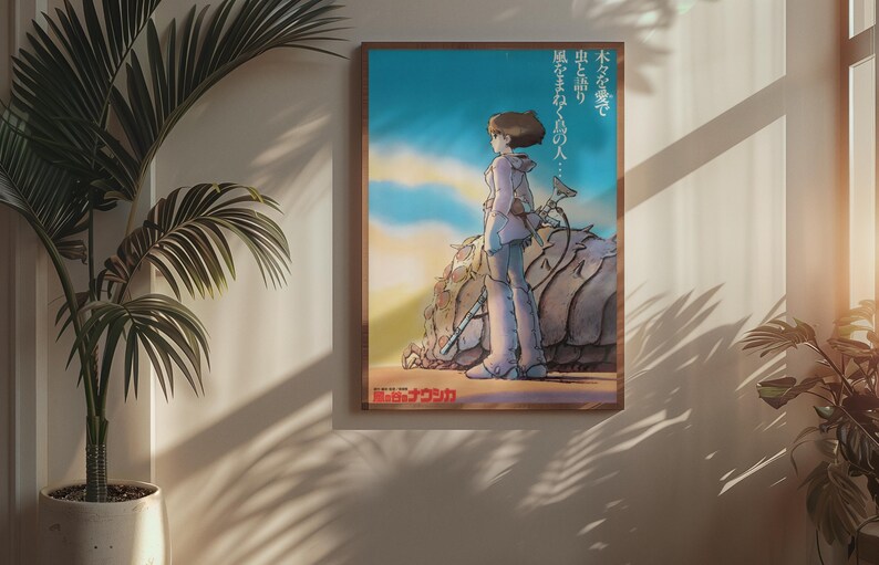 Puede incluir: P&oacute;ster enmarcado con una ilustraci&oacute;n de estilo anime de una persona de pie cerca de una gran formaci&oacute;n rocosa texturizada. La obra de arte tiene una paleta de colores c&aacute;lidos con un cielo azul y una puesta de sol. Texto japon&eacute;s visible.