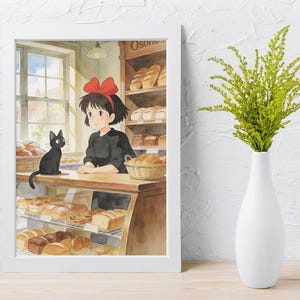 May include: Watercolor print of a bakery scene featuring a young woman with a red bow, a black cat, and various baked goods. The print is framed in a white border and set against a white textured wall. A white vase with green foliage is in the foreground.