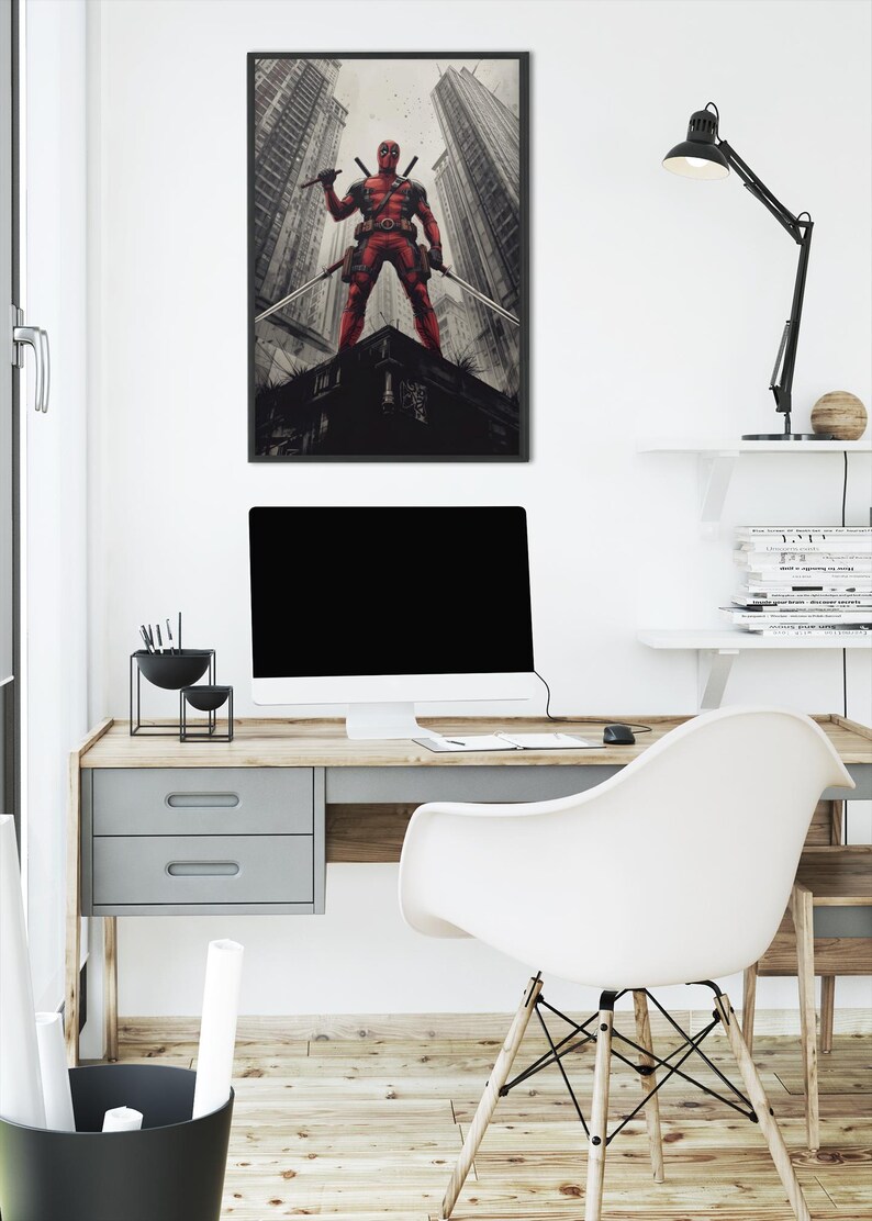 May include: Framed artwork featuring a red costumed figure with two swords, standing on a building rooftop. The background shows tall city buildings. The artwork is displayed above a desk with a computer and a white chair.