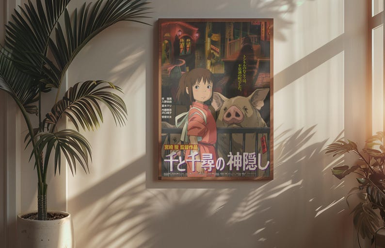 Op de afbeelding: Een ingelijste poster met een sc&egrave;ne uit een animatiefilm. De afbeelding toont een jong meisje in een rode outfit naast een groot varken. Japanse tekst is zichtbaar onderaan. De poster hangt aan een muur naast een potplant.
