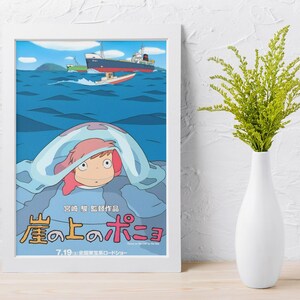 May include: Framed poster featuring a cartoon illustration of a character with pink hair under a blue wave, with ships on the ocean. The poster has Japanese text and is in a white frame. A white vase with green foliage is to the right.
