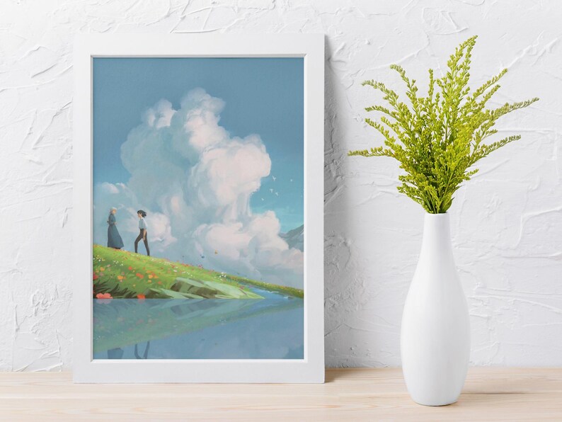 May include: A framed art print depicts a serene landscape with two figures on a grassy hill, overlooking a reflective body of water. The sky is filled with fluffy white clouds. A white vase holds green foliage.