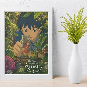 May include: A framed poster featuring artwork from "The Secret World of Arrietty." The image shows a young boy holding a jar with a small girl inside, surrounded by lush green foliage. The poster is in a white frame.