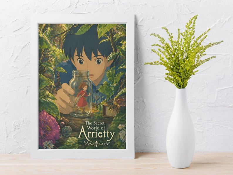 May include: A framed poster featuring artwork from "The Secret World of Arrietty." The image shows a young boy holding a jar with a small girl inside, surrounded by lush green foliage. The poster is in a white frame.