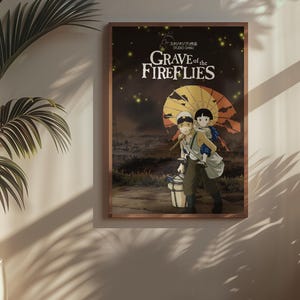 Puede incluir: P&oacute;ster enmarcado de la pel&iacute;cula de anime "La tumba de las luci&eacute;rnagas". La obra muestra a dos figuras caminando, una cargando a la otra, bajo un paraguas amarillo y naranja. El t&iacute;tulo est&aacute; en texto blanco sobre un fondo oscuro.