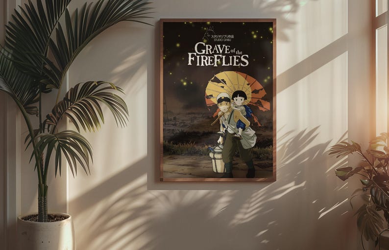 Puede incluir: P&oacute;ster enmarcado de la pel&iacute;cula de anime "La tumba de las luci&eacute;rnagas". La obra muestra a dos figuras caminando, una cargando a la otra, bajo un paraguas amarillo y naranja. El t&iacute;tulo est&aacute; en texto blanco sobre un fondo oscuro.