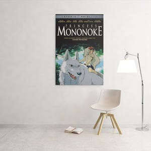 Puede incluir: Un p&oacute;ster enmarcado de la pel&iacute;cula de animaci&oacute;n "La princesa Mononoke" cuelga de una pared blanca. El p&oacute;ster presenta un lobo blanco con una persona montada en su espalda, con el t&iacute;tulo de la pel&iacute;cula en letras grandes.