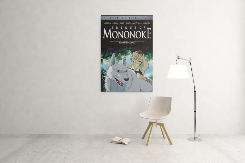 Puede incluir: Un p&oacute;ster enmarcado de la pel&iacute;cula de animaci&oacute;n "La princesa Mononoke" cuelga de una pared blanca. El p&oacute;ster presenta un lobo blanco con una persona montada en su espalda, con el t&iacute;tulo de la pel&iacute;cula en letras grandes.