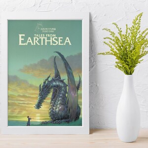 May include: A framed poster featuring the "Tales from Earthsea" movie. The artwork depicts a large, detailed dragon with a person in the foreground, set against a sunset sky. The poster is in a white frame, with a white vase and green plant to the right.
