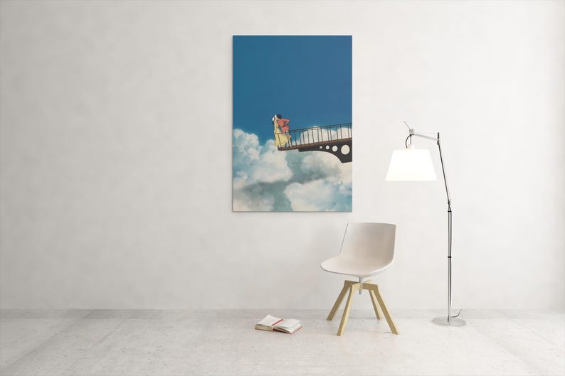 May include: A framed art print depicts a person on a bridge above clouds against a blue sky. The artwork is displayed on a white wall, with a modern chair, a floor lamp, and a book in the foreground.