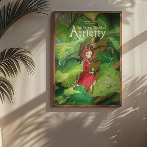 May include: A framed poster of "The Secret World of Arrietty" anime film. The artwork features a young girl in a red dress amidst lush green foliage. The poster is in a wooden frame, hanging on a wall with a potted plant.