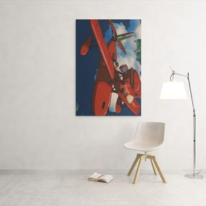 May include: A framed art print featuring a red airplane against a blue sky with clouds. The artwork is displayed on a white wall, with a modern chair and a floor lamp in the foreground. A book is open on the floor.