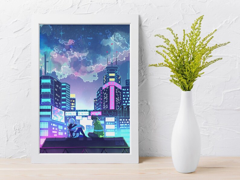 May include: A framed art print showing an anime-style cityscape at night. The artwork features two figures on a rooftop, with buildings lit in neon colours under a cloudy sky. A white vase with green foliage is to the right.
