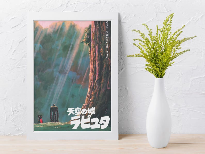 May include: A framed poster with Japanese text and artwork from the animated film "Castle in the Sky." The poster is in a white frame and shows a tall tree, a robot, and two small figures in a colourful, vibrant scene.