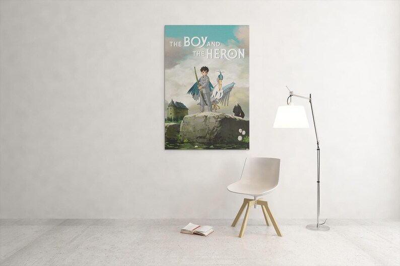 May include: A framed poster titled "THE BOY and the HERON" depicts a boy with a heron on a rock. The artwork features a castle, a dark figure, and a cloudy sky. A white chair, a floor lamp, and a book are in the room.