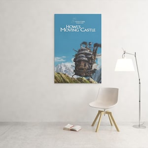 May include: A poster of Howl's Moving Castle hangs on a white wall. The poster features the animated castle against a blue sky and mountains. A white chair, a book, and a lamp are in front of the wall.
