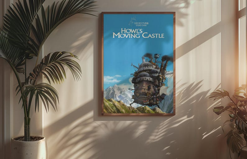 May include: A framed poster featuring the animated film "Howl's Moving Castle." The artwork depicts the castle with a blue sky background and mountains. The poster is in a wooden frame and hangs on a wall.