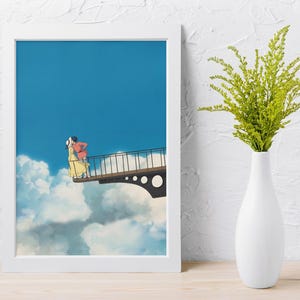 May include: A framed art print featuring an animated scene of two figures embracing on a bridge against a blue sky and cloud backdrop. The print is in a white frame, with a white vase holding green foliage to the right.