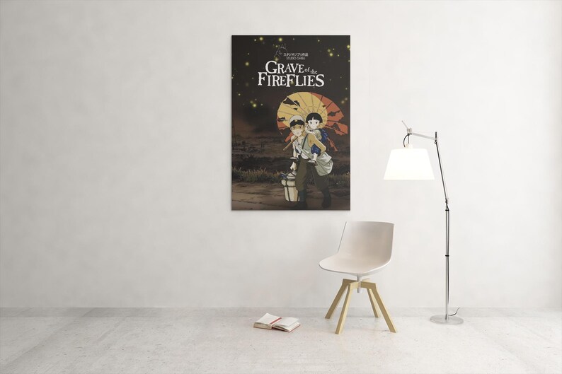 Puede incluir: Un p&oacute;ster de la pel&iacute;cula de animaci&oacute;n "La tumba de las luci&eacute;rnagas" cuelga de una pared blanca. El p&oacute;ster muestra a dos ni&ntilde;os bajo un paraguas amarillo, con el t&iacute;tulo de la pel&iacute;cula en texto blanco. Una silla blanca, una l&aacute;mpara y un libro est&aacute;n frente a la pared.