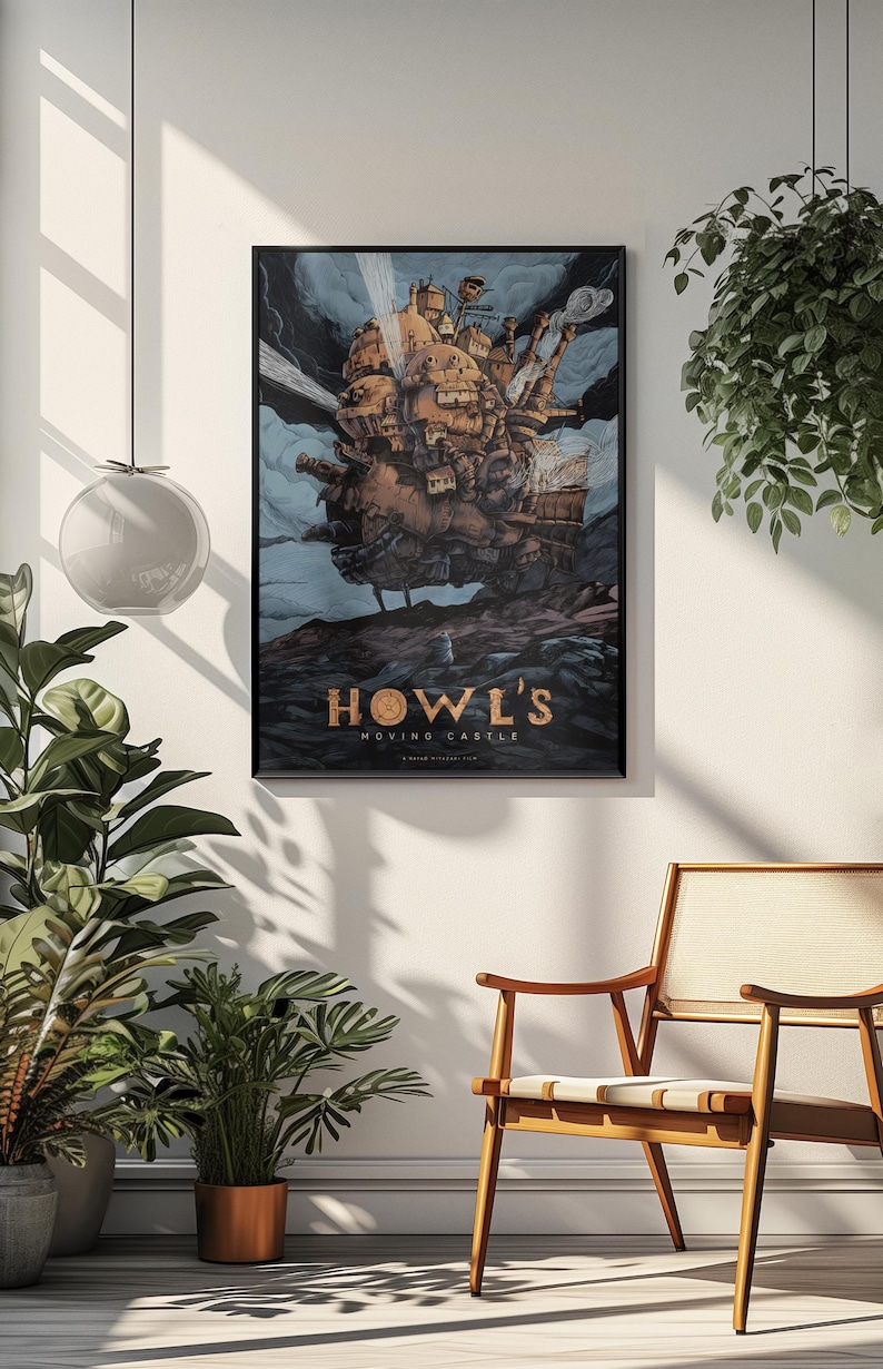 May include: A framed poster of Howl's Moving Castle, featuring the animated castle in shades of brown and tan against a cloudy blue sky. The title is in gold lettering. The poster is hanging on a white wall.