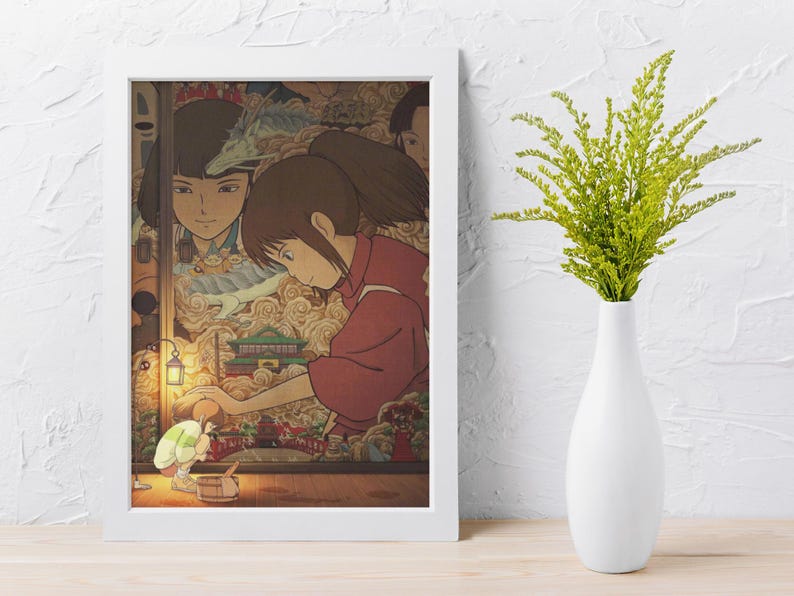 May include: A framed print of an animated film scene. It shows a girl in a red outfit, interacting with a small figure near a table. The background features other characters and a detailed, colourful landscape.