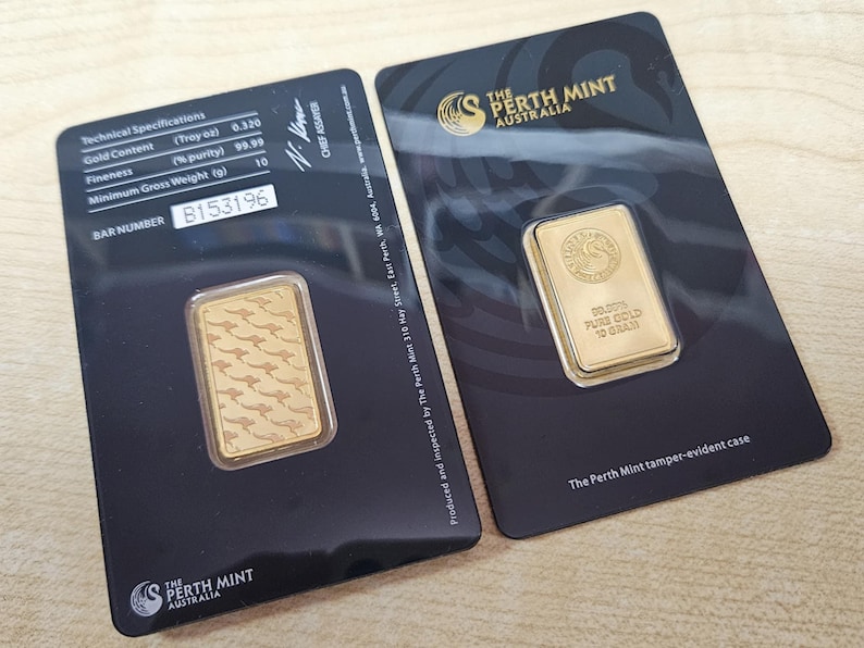 K&ouml;nnte beinhalten: Zwei Goldbarren von The Perth Mint, jeweils in einer schwarzen Karte. Ein Barren zeigt ein K&auml;nguru-Muster, der andere das Logo der M&uuml;nze und die Aufschrift "99,99% reines Gold 10 Gramm". Die Karten enthalten technische Daten.